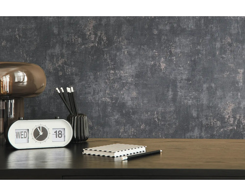 Interior decorativ cu lampă, ceas de masă, blocnotes și creioane pe o masă în fața unui perete texturat