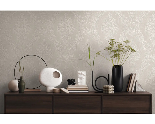 Decor de perete cu tapet bej și model clasic pe o comodă cu vaze decorative și cărți