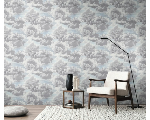 O cameră cu tapet cu model de nori, un fotoliu, o lampă de podea și o măsuță laterală.