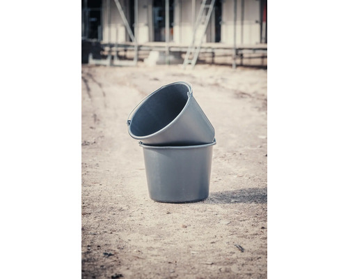 Două cuve de mortar din plastic stivuite una peste alta pe un șantier.