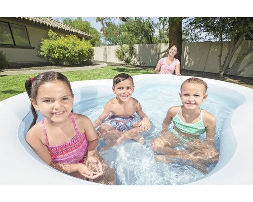 Copii se joacă într-o piscină gonflabilă în grădină.