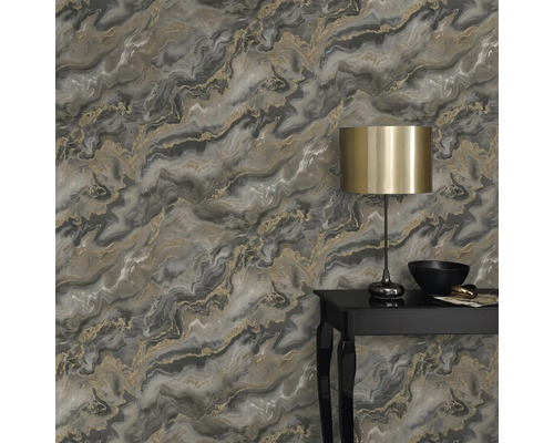 Prim-plan cu un perete cu tapet marmorat în tonuri de gri și aur, decorat cu o lampă și obiecte decorative pe o masă