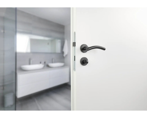 Ușă albă cu clanță neagră și baie în fundal