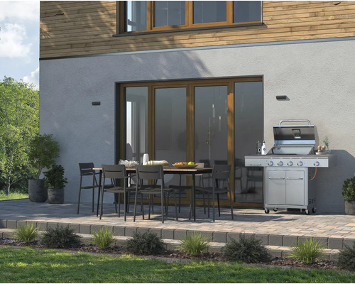 Spațiu exterior cu grătar, masă de grădină și scaune în fața casei