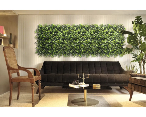 Interior decorativ cu panou de perete cu plante deasupra unei canapele negre.