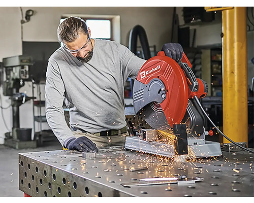 Un bărbat operează un ferăstrău circular pentru metal Einhell într-un atelier, sar scântei.