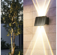 Lampa de perete solară cu raze de lumină pe un perete de casă