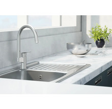 Chiuvetă din oțel inoxidabil cu robinet într-o bucătărie luminoasă.