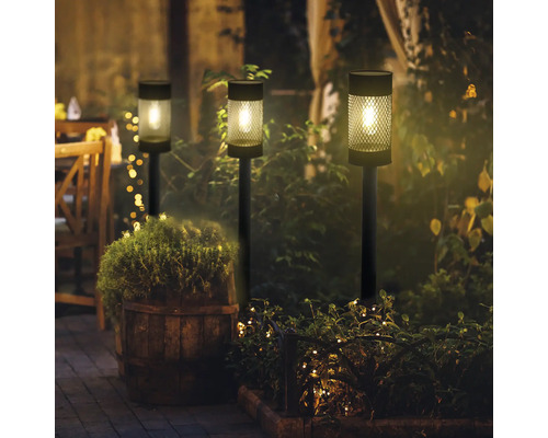 Trei lămpi solare în grădină pe timp de noapte, creând o atmosferă plăcută.