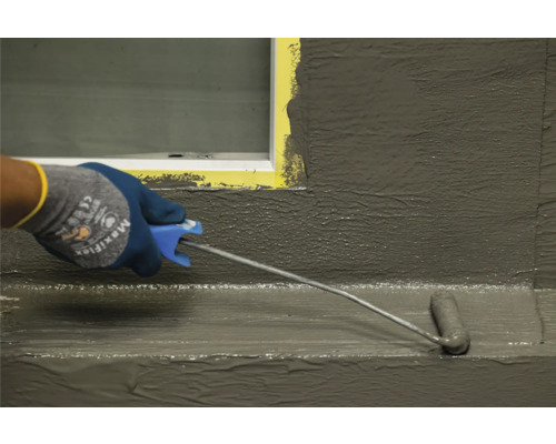 Aplicarea unei șlamuri de etanșare cu o rolă de vopsea pe un perete