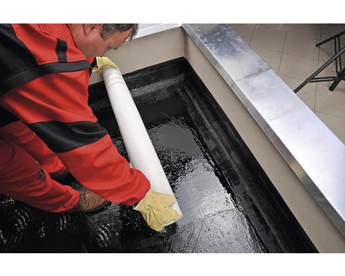 Artizan montează folie de etanșare pe o terasă pe acoperiș