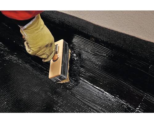 Aplicarea impermeabilizării bituminoase cu o perie pe o suprafață.