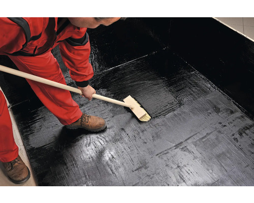 O persoană aplică un strat impermeabil cu o perie.