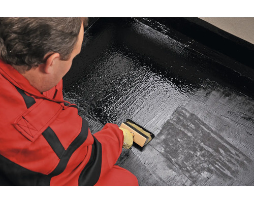 O persoană aplică un strat pe o suprafață cu o pensulă.