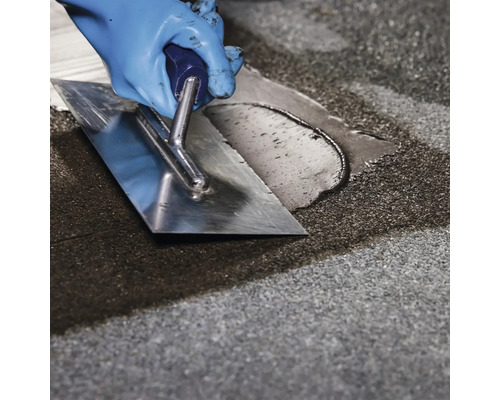 Artizan nivelează șapa autonivelantă cu o mistrie