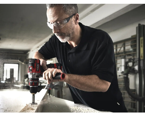 Un bărbat face o gaură într-o piesă de lucru cu o mașină de găurit cu acumulator.