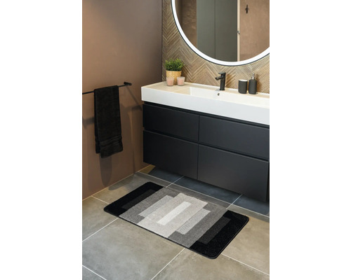 Baie cu chiuvetă, oglindă și covor de baie în nuanțe de gri.