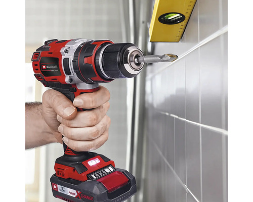 O persoană găurește un perete faianțat cu o șurubelniță cu acumulator marca Einhell. Un boloboc este atașat pentru aliniere.