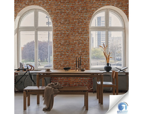 Sufragerie cu masă din lemn, bancă și scaun în fața unui perete de cărămidă cu două ferestre mari