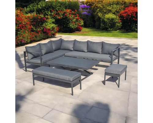 Set mobilier de grădină cu canapea de colț, masă, bancă și taburet pe o terasă în fața straturilor de flori