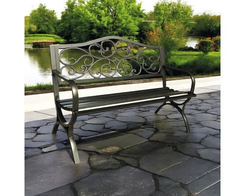 Bancă de grădină metalică cu detalii ornamentate în fața unui lac