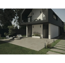 Vedere exterioară a unei case moderne cu terasă, mobilier de grădină și pavaj