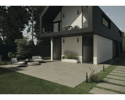 Vedere exterioară a unei case moderne cu terasă, mobilier de grădină și pavaj