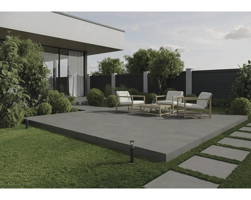 Terasa cu mobilier de grădină pe plăci de beton, înconjurată de gazon și plante.