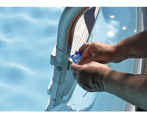 O persoană fixează un termometru albastru cu cablu pe o scară de piscină