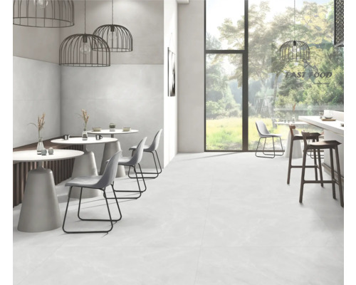 Cameră luminoasă cu pardoseală de gresie, mese și scaune.