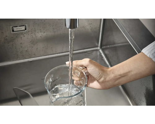 Un pahar gradat este umplut cu apă într-o chiuvetă.