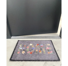 Covoraș de ușă cu model floral și cuvântul Acasă în fața unei uși