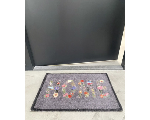 Covoraș de ușă cu model floral și cuvântul Acasă în fața unei uși