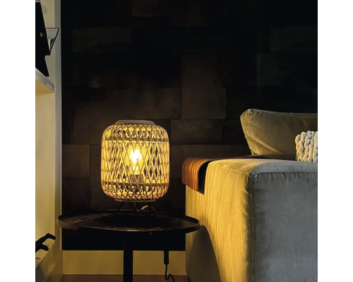 Lampă de masă decorativă din ratan lângă o canapea pe o masă