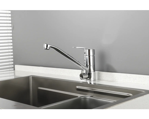 Baterie de chiuvetă metalică lângă o chiuvetă din oțel inoxidabil