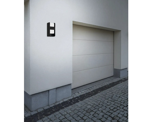 Lumină modernă de perete pentru exterior montată lângă un garaj pe peretele unei case