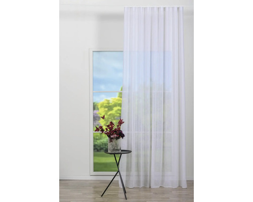 Scenă cu o perdea albă la fereastră și o masă cu o vază cu flori