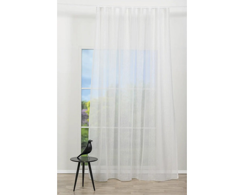 Fereastră cu perdea albă transparentă și decorațiune pe o masă mică