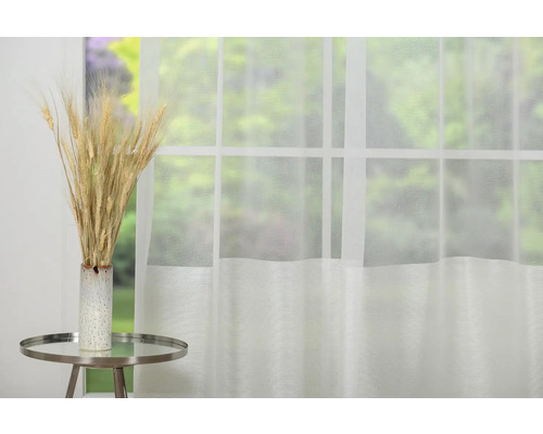 Spice decorative de grâu în vază pe masă în fața ferestrei cu perdea.