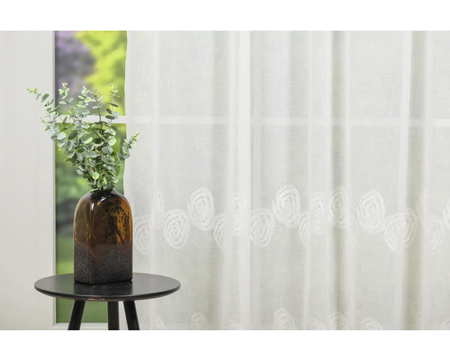 Perdea decorativă, transparentă, cu model de trandafiri, în fața unei ferestre