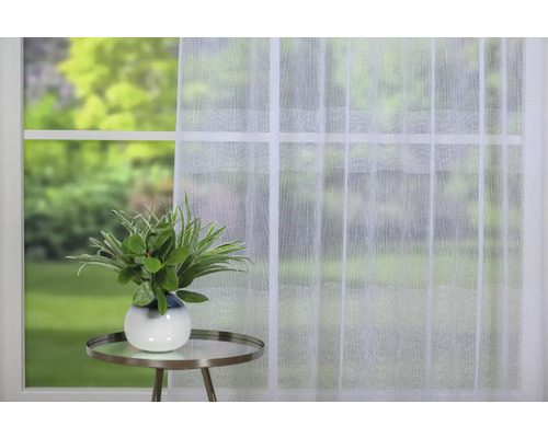 Fereastră cu perdea panou albă, transparentă și plantă pe o masă