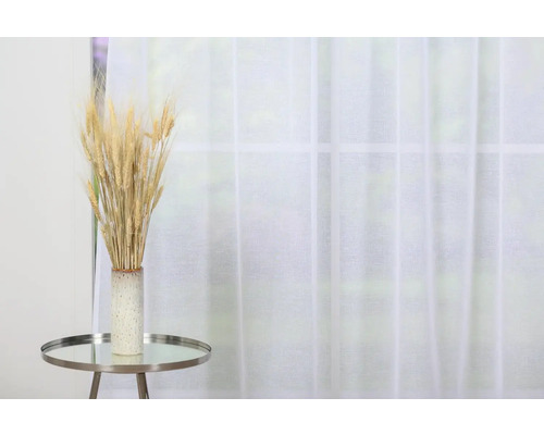 Spice decorative de grâu într-o vază pe o măsuță laterală în fața unei ferestre cu perdea.