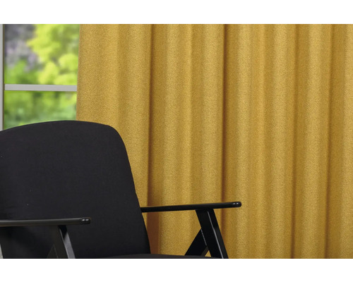 Vedere cu un fotoliu negru și o perdea galbenă în fața unei ferestre