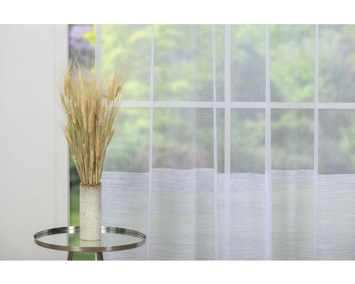 Spice decorative de grâu într-o vază pe o masă în fața unei ferestre cu perdea.