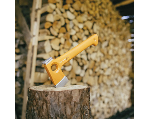Topor Fiskars pe un butuc de lemn în fața unei grămezi de lemn