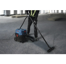 Un bărbat folosește un aspirator industrial Bosch pentru a curăța o clădire în construcție.