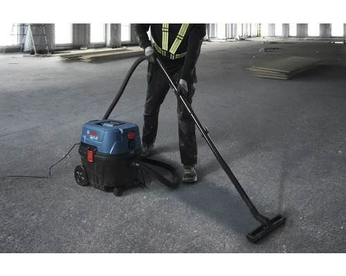 Un bărbat folosește un aspirator industrial Bosch pentru a curăța o clădire în construcție.