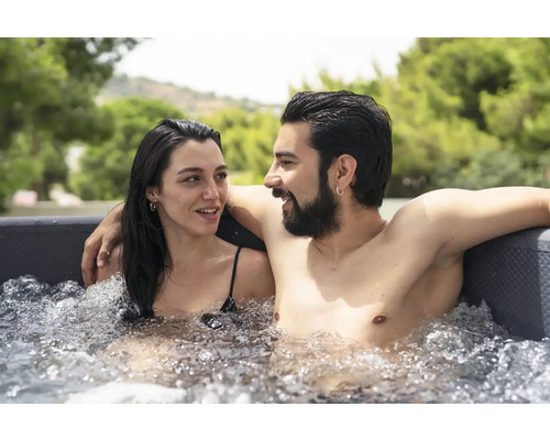 Un cuplu se relaxează într-un jacuzzi umplut cu apă afară.