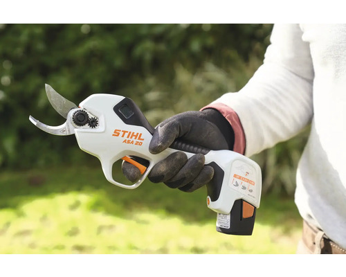 O persoană ține în mână un foarfece de pomi cu acumulator Stihl ASA 20.