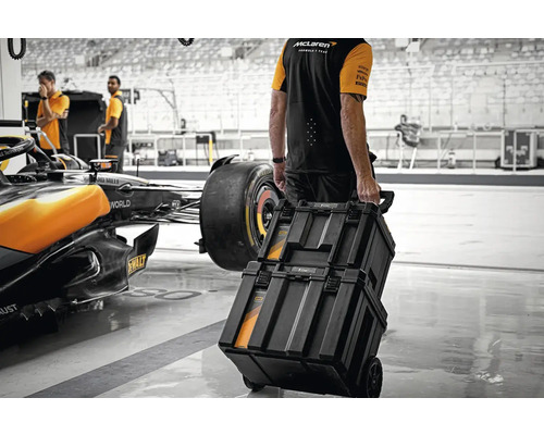 Persoană trăgând cutii de scule pe roți într-un atelier